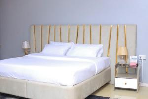 a bedroom with a large white bed with a wooden headboard at BUDDIEZ hotel limited in Kampala +2 photos