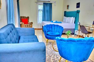 a living room with blue chairs and a bed at Potato Suites n Spa in Gaborone