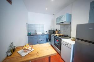 a kitchen with blue cabinets and a wooden table at La Belle Vue - Gîte 3 étoiles Eco Responsable Climatisé in Maury