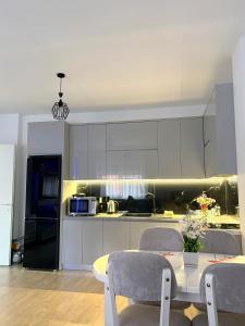 a kitchen with white cabinets and a table with chairs at Mme apartment in Kamëz