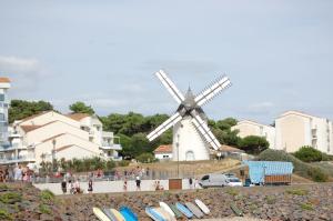 a windmill on the beach next to some buildings at Studio proche océan pour Deux personnes in Longeville-sur-Mer
