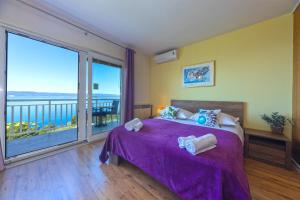 a bedroom with a purple bed with a large window at Villa Vineyard oaza in Brela +64 photos