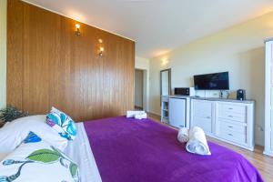 a bedroom with a large bed with a purple blanket at Villa Vineyard oaza in Brela