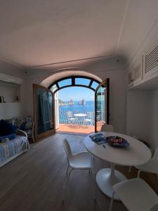 a living room with a table and a view of the ocean at Casa vista Faraglioni Capri in Capri