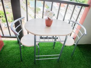 a table and chairs on a balcony with a vase of flowers at Althea's Horizon Stay - Primeworld District in Pajak