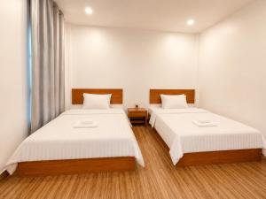 two beds in a room with white walls and wood floors at Ah Gong Boutique Bungalows in Sihanoukville