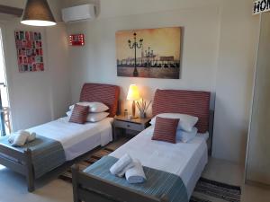 a bedroom with two beds and a table with a lamp at 2BR Gouvia – Apt 6 in Gouvia