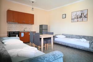a room with two beds and a table and a kitchen at Mandi's Apartment in Ksamil