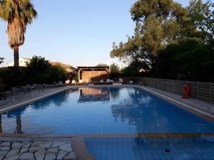 a large swimming pool with chairs and a palm tree at Value Stay for 4 – Apt 11 in Gouvia