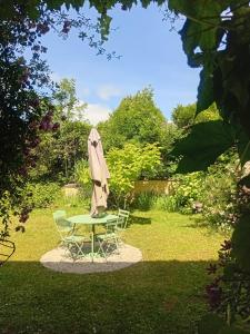 a table with an umbrella and a table with a chair at Le Tilleul du Perche - Jardin clos - Fibre - Télétravail - Parking privé in La Ventrouze