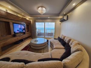 a living room with a large couch and a flat screen tv at Alex dream in Alexandria