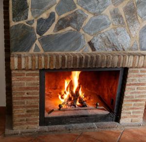 a brick fireplace with a fire in it at Los Meri in Grazalema