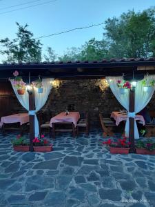a patio with two tables and white curtains at Guest House Popov in Marchevo