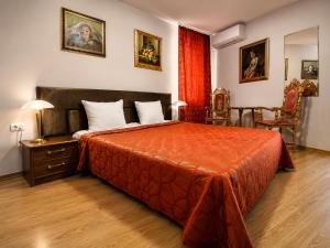 a bedroom with a bed with a orange bedspread at Family Art Hotel Gallery in Pleven