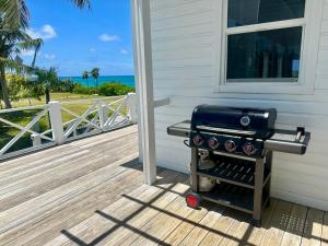 a grill sitting on a porch next to a house at Eleuthera Retreat - Private Villa & Cottages on pink sand beachfront in North Palmetto Point