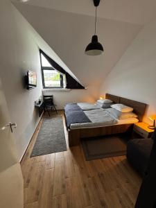 a attic bedroom with a bed and a window at Megacentrum Szállás in Szekszárd +18 photos
