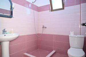 a pink bathroom with a toilet and a sink at Mandi's Apartment in Ksamil +24 photos