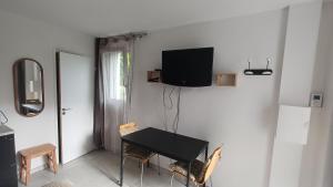 a room with a table and a television on a wall at Le Cozy Cocon in Franqueville-Saint-Pierre