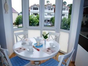 una mesa blanca y sillas en una habitación con ventanas en Strandstraße by Rujana en Baabe