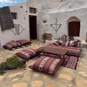 a patio with pillows and a table and a house at Dar Sana in Qaşr al Ḩallūf