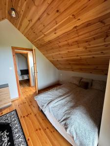 a bed in a room with a wooden ceiling at Rumelówka in Wawrowice