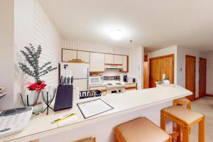 a kitchen with a white counter with chairs and a desk at Ober Tal Getaway in Stratton