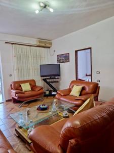 a living room with leather furniture and a tv at Himara Holiday House in Himare