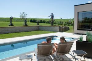 a man and woman sitting in chairs next to a swimming pool at Eifelvilla Weber in Arenrath +28 photos