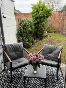 two chairs and a table with a vase of flowers on a patio at Tomorrowland Home in Boom