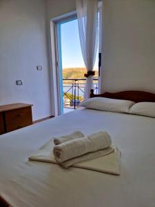 a white bed with a towel on it with a window at Himara Holiday House in Himare