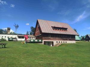 a large barn with a red roof on a field at Penzion Athena in Velenov