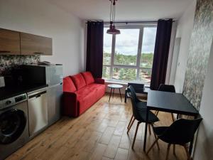 a living room with a red couch and a table at Apartamenty Owocowe in Rowy