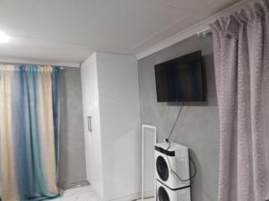 a room with a tv on a wall with curtains at Vumasky 2 in Ladysmith