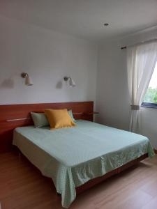 a bedroom with a bed with a green comforter and a window at Maroiço Residence in Madalena