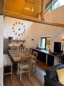 a kitchen and dining room with a table and a clock at Greystone Cabin in Măguri-Răcătău