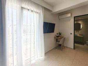 a room with a large window with a chair and a desk at Aeolia Seaside Hotel in Kardamaina