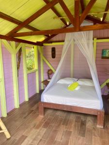 a bed in a room with a wooden floor at Kaz Robinson Cabane Perchee Vue Mer Vivez l aventure Robinson avec le confort d une vue imprenable sur les Caraibes in Terre-de-Bas