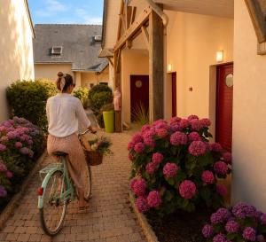 a woman riding a bike next to pink flowers at APPART HÔTEL MON CALME in Piriac-sur-Mer