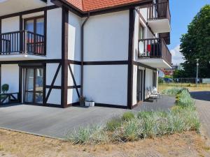 a white building with a deck and a balcony at Apartamenty Owocowe in Rowy