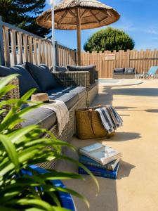 a couch and books on a patio with an umbrella at Domaine MON CALME in Piriac-sur-Mer