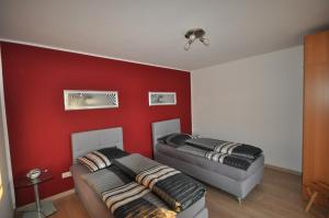 two beds in a room with a red wall at Gästehaus Brinkmann am Moor in Spenge