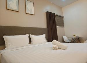 a bedroom with a white bed with a towel on it at Windsor Lane Hostel Ipoh in Ipoh