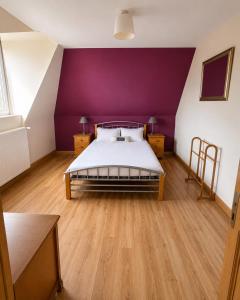 a bedroom with a bed with a purple wall at La Ferme des Coquelicots in Miraumont