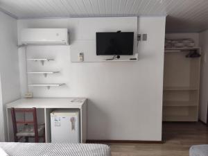 a room with a white wall with a tv on it at Recanto Vó Eni in Gramado