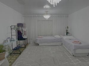 a white room with two beds and a chandelier at Friendly House in Bokonbayevo
