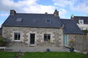 a stone house with a black roof at maison pour vieilles charrues in Maël-Carhaix