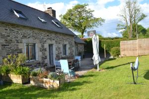 a stone cottage with a patio and an umbrella at maison pour vieilles charrues in Maël-Carhaix