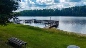 a park bench sitting on the grass near a lake at Apartament Jeziorna in Debrzno