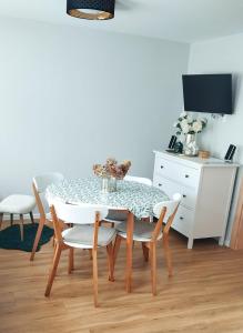 a dining room with a table and chairs and a white cabinet at Apartament Jeziorna in Debrzno