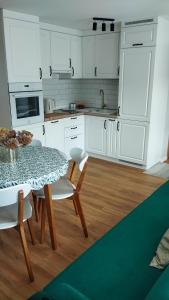 a kitchen with white cabinets and a table and chairs at Apartament Jeziorna in Debrzno